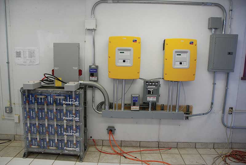 Photo 5. Energy storage system (ESS) as part of a battery-backed-up PV system. Disconnect circuit breakers are on top of the batteries on the left side of the picture. Courtesy of John Wiles