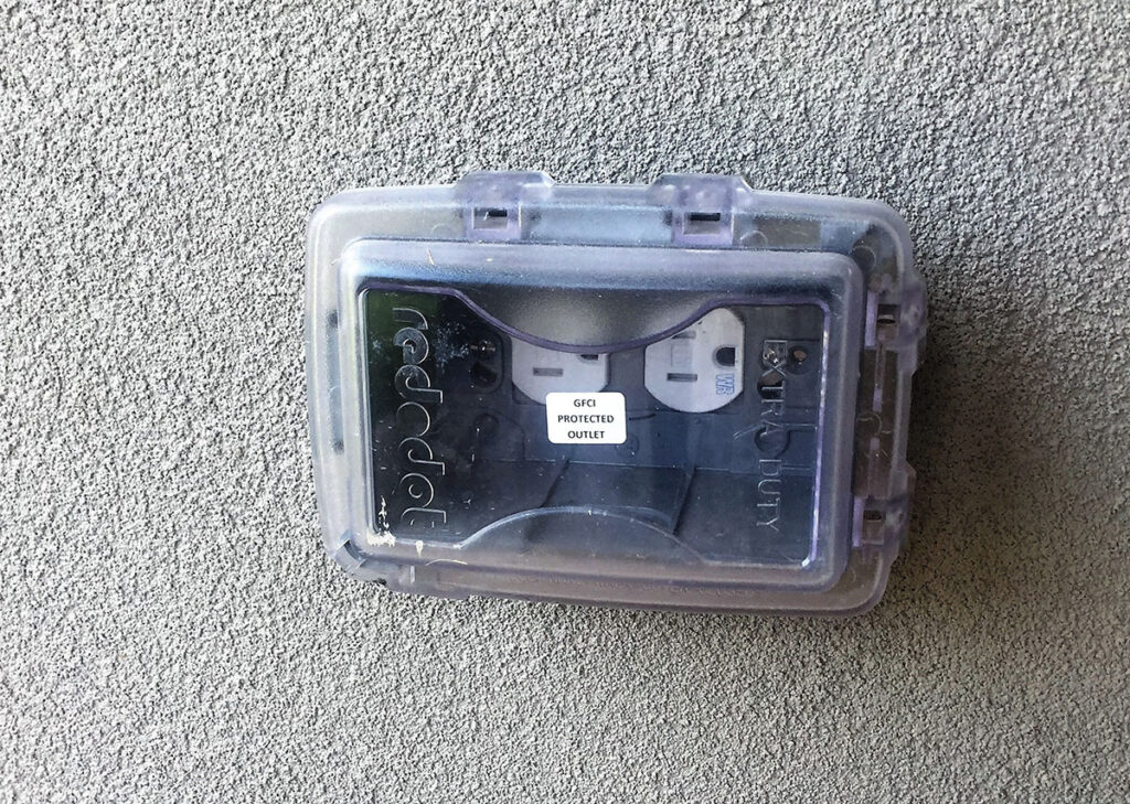 Photo 2a. A receptacle outlet located in a wet location with the appropriate cover and marked as having GFCI protection.